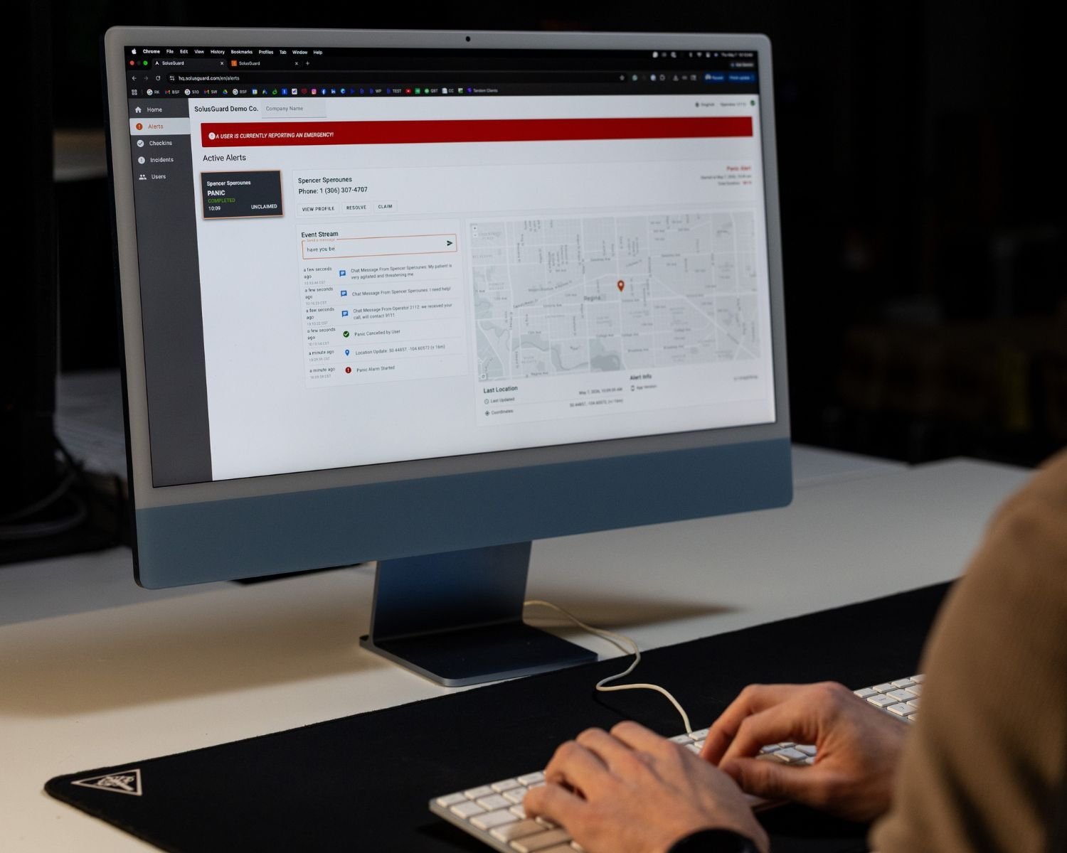 An operator at a desktop running Command Center, with the active alert queue, event stream, and location map on screen
